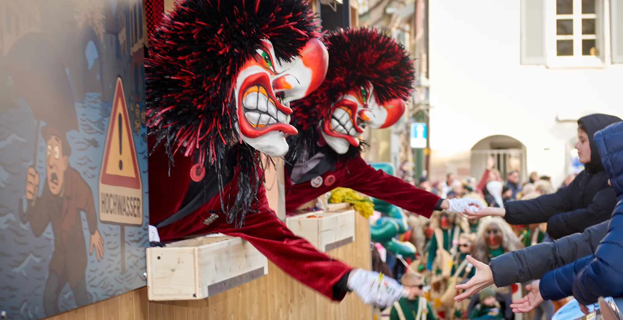 Rote Fasnachtsmaske mit schwarzem Haar bei Parade