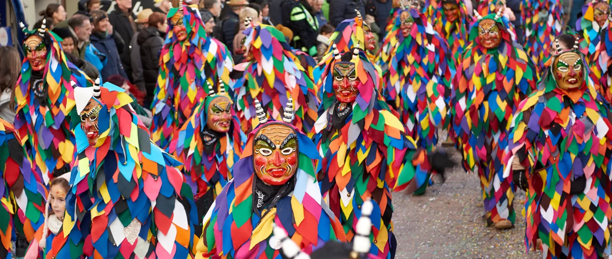 Fasnächtler in bunten Harlekin-Kostümen und Masken